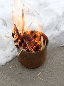 Palms burn in a canister next to a snow bank